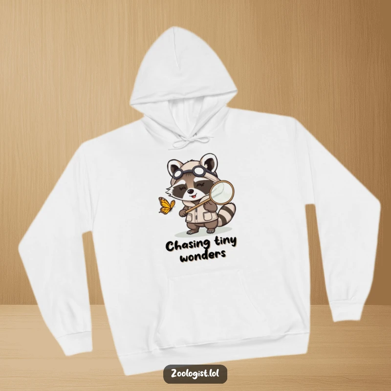 Funny Kawaii raccoon zoologist character chasing a butterfly with a net, a warm and humorous hoodie for nature explorers.