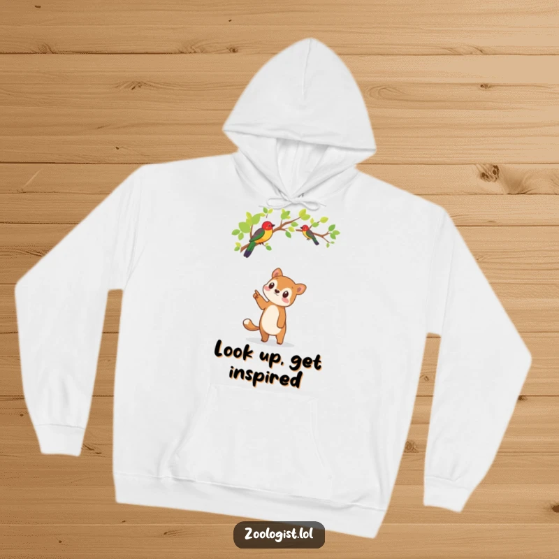 Funny cozy hoodie depicting a cute animal character looking with fascination upwards at a strikingly colorful bird in a leafy tree.